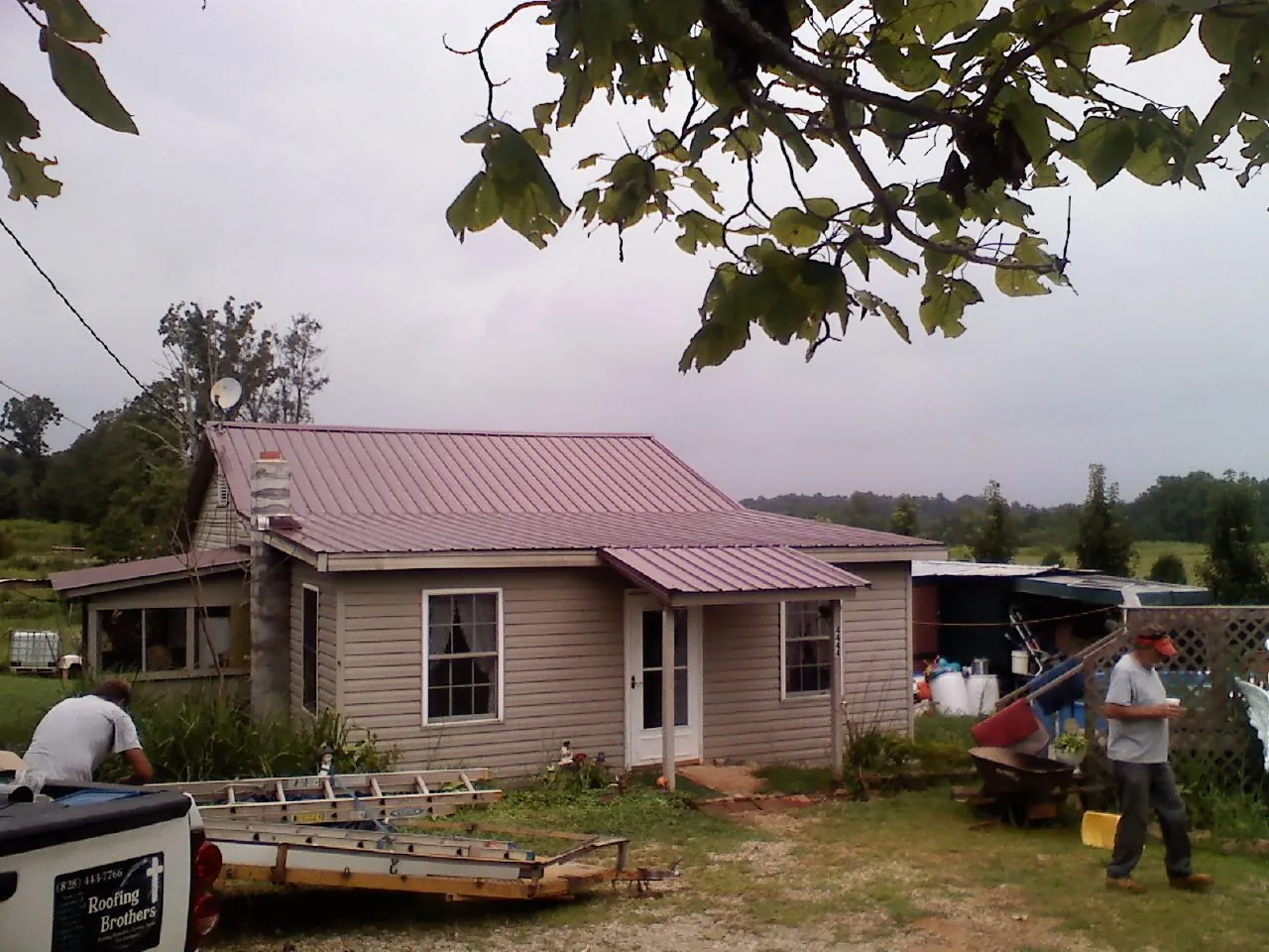 Crew finishing a mauve metal roof on a small farmhouse in Glencoe
